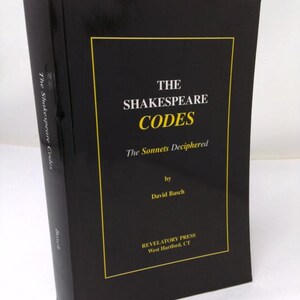 May include: A black hardcover book titled The Shakespeare Codes: The Sonnets Deciphered by David Basch, published by Revelatory Press in West Hartford, CT. The cover features white and yellow text enclosed within a thin yellow rectangular border.