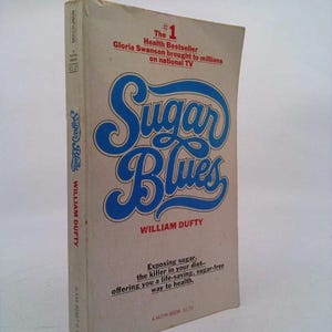 May include: A book cover with a blue and white title "Sugar Blues" by William Duffy. The book is a health bestseller that exposes sugar as a killer in your diet and offers a life-saving, sugar-free way to health.