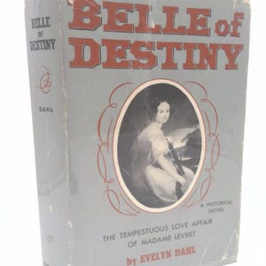 May include: A vintage book titled "Belle of Destiny" by Evelyn Dahl. The cover features a portrait of a woman in an oval frame, with text in red and white. The book is a historical novel about the tempestuous love affair of Madame LeVert.