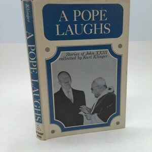 May include: A vintage book titled "A Pope Laughs" with a blue and white cover. The cover features the title in large white letters on a blue background, with a photo of two men. The book's spine also displays the title.