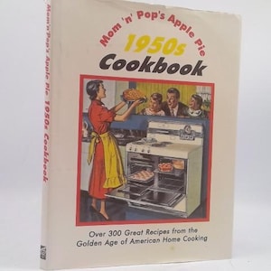 May include: A vintage cookbook titled "Mom 'n' Pop's 1950s Cookbook" with a retro illustration of a woman in a red dress and yellow apron holding a pie. The cover features text and a kitchen scene, evoking the Golden Age of American Home Cooking.