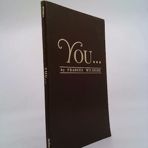 May include: A dark brown book with the title "You..." by Frances Wilshire. The title is in gold lettering with a decorative flourish.