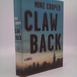 May include: A hardcover book titled "Claw Back" by Mike Cooper. The book has a blue cover with the title in large, dark letters. The cover features a cityscape silhouette at the bottom. The spine also displays the author's name and title.