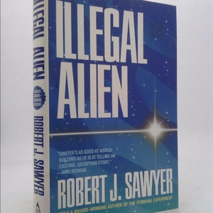 May include: A blue book cover with the title "Illegal Alien" in white text. The author is Robert J. Sawyer, and the book is described as a Nebula Award-winning novel.
