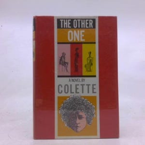 May include: A hardcover book titled "The Other One" by Colette. The cover is red with a central panel featuring illustrations and the title in bold white letters. The author's name is also displayed.