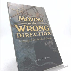 May include: Book cover with a blue and white illustration of a ship on the sea. The title is "Moving in the Wrong Direction" and the subtitle is "A Study of the Book of Jonah". The author is Dr. Karry D. Wesley.