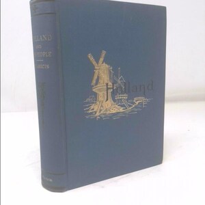 May include: A hardcover book titled "Holland and Its People" with a blue cover. The cover features a gold illustration of windmills and the word "Holland". The spine also has gold lettering.
