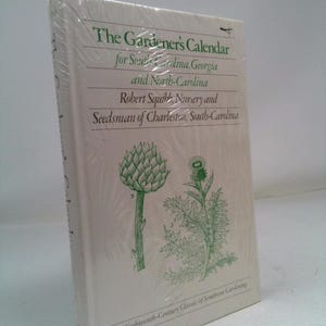 May include: A white book titled "The Gardener's Calendar" for South Carolina, Georgia, and North Carolina. The cover features green botanical illustrations and text. The book is wrapped in clear plastic.