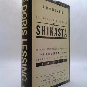 May include: A black and white book cover with the title "Shikasta" and the author "Doris Lessing". The book is part of a series called "Archives: Re: Colonised Planet".