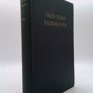 May include: A black hardcover book with gold lettering on the spine and front cover. The title is "Old-Time Fairhaven".