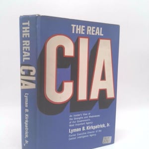 May include: A blue hardcover book titled The Real CIA by Lyman B. Kirkpatrick, Jr. The front cover features large white letters spelling CIA with a black drop shadow. The subtitle reads An Insider's View of the Strengths and Weaknesses.