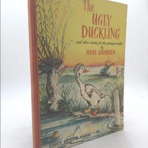 May include: The cover of a children's book titled "The Ugly Duckling" and other stories for the younger reader by Hans Andersen. The cover features a cartoon illustration of a duckling in a pond with a frog and a tree in the background. The book is part of the Early Reader Series - 32.