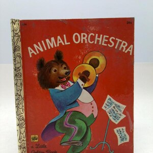 May include: Vintage "Animal Orchestra" Little Golden Book. The cover features a bear playing cymbals, dressed in a blue jacket and green pants. The book has a red background with white text and a decorative spine.