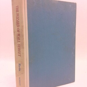 May include: A blue hardcover book with the title "The Wizard of Wall Street" by Martin  Morrow.