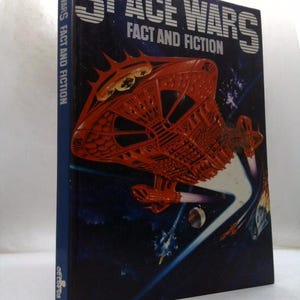 May include: A hardcover book titled Space Wars Fact and Fiction with a dark blue background. The cover features a large, detailed orange spaceship flying through space, emitting light trails. The title is printed in bold white letters.