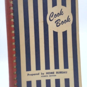May include: A vintage cookbook with a blue and white striped cover. The title "Cook Book" is in a white circle with blue lettering. The text "Prepared by HOME BUREAU FOURTH EDITION" is printed below the title.