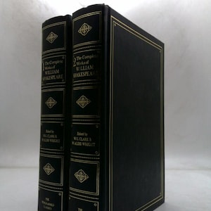May include: Two hardcover books, "The Complete Works of William Shakespeare," in a black and gold design. The spines feature gold lettering and decorative elements. The books are part of "The Programmed Classics" series.
