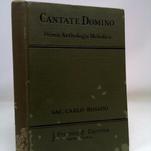 May include: A vintage book titled "CANTATE DOMINO" with the subtitle "Prima Anthologia Melodica." The cover is a faded olive green with black text. The author's name, SAC. CARLO ROSSINI, and the publisher, J. FISCHER & BROTHER, are also visible.