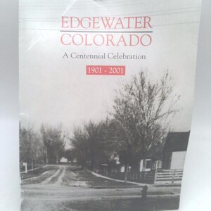 May include: A softcover book titled Edgewater Colorado A Centennial Celebration 1901-2001. The cover features a black and white photograph of a tree-lined street with a fire hydrant and a house, with red text for the title and date box.