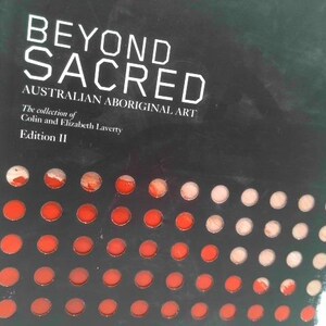May include: A book cover with the title "BEYOND SACRED" in white capital letters. Below, it reads "AUSTRALIAN ABORIGINAL ART". The cover is black with a pattern of red and white circles. The spine reads "BEYOND SACRED" and "AUSTRALIAN ABORIGINAL ART".