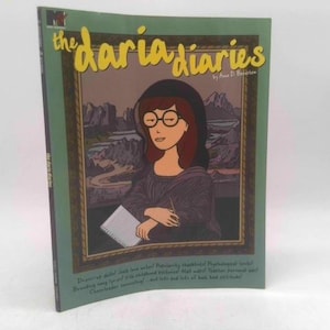 May include: A softcover book titled The Daria Diaries by Anne D. Bernstein. The cover features a cartoon illustration of Daria Morgendorffer styled like the Mona Lisa, wearing a dark top, glasses, and holding a notebook against a landscape background.