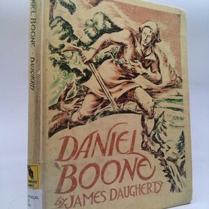 May include: A vintage book cover with a tan background and a colorful illustration of a man running through the woods with a rifle. The title of the book is "Daniel Boone" by James Daugherty.