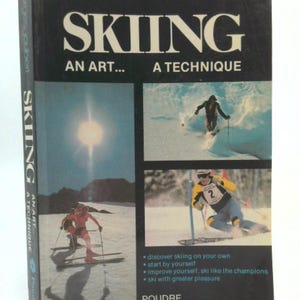 May include: A vintage book titled "SKIING" by Georges Joubert. The cover features skiers in action, with the text "AN ART... A TECHNIQUE." The book's spine also displays the title and author. The publisher is POUDRE.
