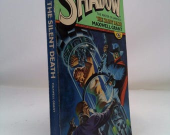 May include: Vintage paperback book titled "The Shadow" with the text "The Silent Death" by Maxwell Grant. The cover features a green and blue illustration of a man in a glass chamber, with other figures in the background.