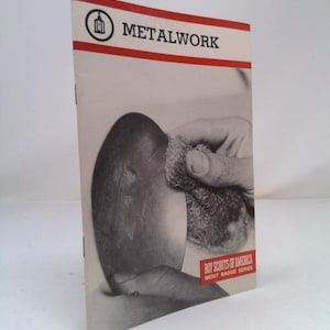 May include: A vintage Boy Scouts of America merit badge booklet for metalwork. The cover features a black and white photo of a hand sanding a metal object.