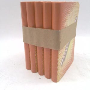 May include: A stack of orange-colored rectangular items, bound together with a brown paper band. The items have a ridged edge and a printed design on the side. The overall shape is a rectangular prism.