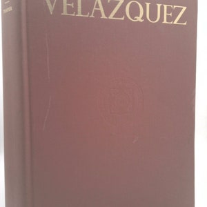 May include: A maroon hardcover book with the title "VELAZQUEZ" in gold lettering. The book is published by The Hispanic Society of America.