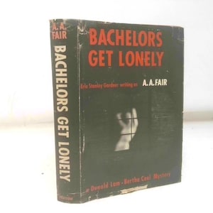 May include: A vintage hardcover book titled "Bachelors Get Lonely" by A.A. Fair. The book has a dark cover with red lettering and a black and white image. The spine also features the title. A classic mystery novel.