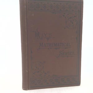 May include: A vintage brown book titled "Ray's Mathematical Series." The cover features decorative floral and geometric patterns in a darker shade of brown. The book is standing upright against a white background.
