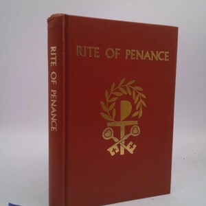 May include: A red hardcover book with gold lettering titled "Rite of Penance". The book has a gold illustration of a cross with keys and a wreath on the front cover.