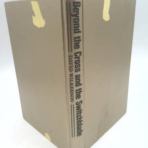 May include: A tan hardcover book with the title "Beyond the Cross and the Switchblade" by David Wilkerson.