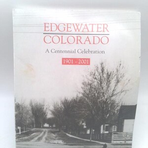 May include: A softcover book titled Edgewater Colorado A Centennial Celebration 1901-2001. The cover features a black and white historical photograph of a dirt road, trees, and a house, with red text for the title and the date range 1901-2001.