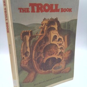 May include: A vintage copy of "The Troll Book" by Michael Berenstain. The book cover features a whimsical illustration of a troll-like figure with a castle-like structure built into its body. The title is in red block letters.