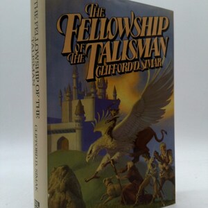May include: The Fellowship of the Talisman book cover features a fantasy illustration of a griffin flying over a castle with a group of people and a dog. The book title is "The Fellowship of the Talisman" by Clifford D. Simak.