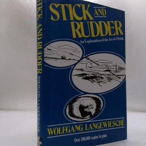 May include: A hardcover book titled Stick and Rudder: An Explanation of the Art of Flying by Wolfgang Langewiesche. The blue cover features yellow text and three oval illustrations depicting airplanes in flight and a pilot in a cockpit.