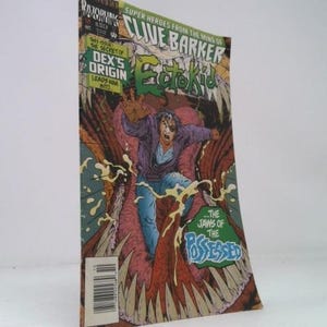 May include: A comic book titled "Ectokid" by Clive Barker. The cover features a man falling into a monster's mouth. The comic has the text "Dex's Origin Leads Him Into... The Jaws of the Possessed."