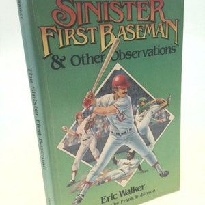 May include: A green book cover with the title "The Sinister First Baseman & Other Observations" in yellow and red lettering. The cover features a baseball player in a red hat and white uniform holding a bat. The author's name, Eric Walker, is printed in white lettering at the bottom of the cover.