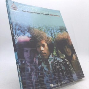 May include: A book titled "Highlights From The Jimi Hendrix Experience BBC Sessions" featuring a photo of the band. The cover has the text "Guitar Recorded Versions" and the Hal Leonard logo. The book is wrapped in plastic.