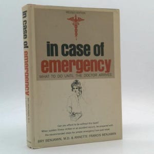 May include: A vintage book titled "In Case of Emergency" with a beige cover. The title is in large black and red letters. The book's spine reads "In case of emergency". A medical symbol is at the top.