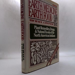 May include: A hardcover book titled "Earth Medicine Earth Food" by Michael A. Weiner. The cover features text in red and white, with a green panel containing additional text about plant remedies and natural foods of North American Indians. The book has over 150 illustrations.