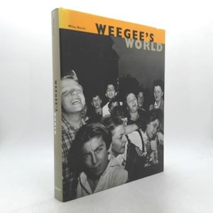 May include: A hardcover book titled "Weegee's World" by Miles Barth. The cover features a black and white photograph of a crowd of people looking upwards. The book's spine is visible, with the title printed vertically.