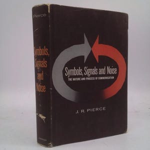 May include: A hardcover book titled "Symbols, Signals and Noise" by J.R. Pierce. The book has a dark brown cover with white and orange text and a graphic of two arrows. The spine displays the title in gold lettering.