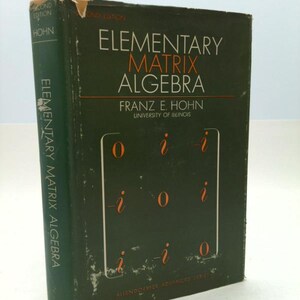 May include: A hardcover book titled "Elementary Matrix Algebra" by Franz E. Hohn, University of Illinois. The book has a dark green cover with white and orange text. The spine reads "Elementary Matrix Algebra" vertically.