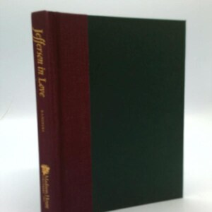 May include: A hardcover book titled "Jefferson in Love." The book has a dark green cover with a burgundy spine. The title is printed vertically in gold lettering. The book is a historical fiction novel.