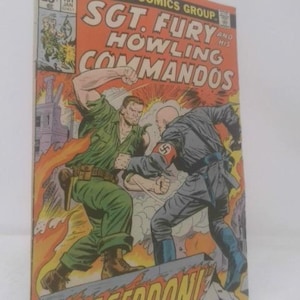 May include: A vintage Sgt. Fury and His Howling Commandos comic book featuring a colorful cover illustration of a soldier in a green uniform punching a bald figure in a dark grey uniform with a red armband. The title text is printed in bold white.