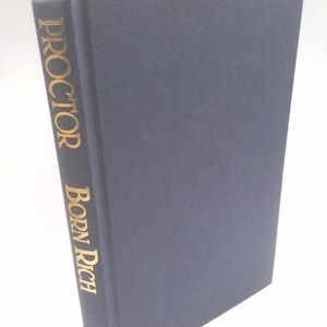May include: A hardcover book titled "Born Rich" by Proctor. The book has a dark blue cover and gold lettering on the spine. The book is angled slightly, showcasing the title and author's name.